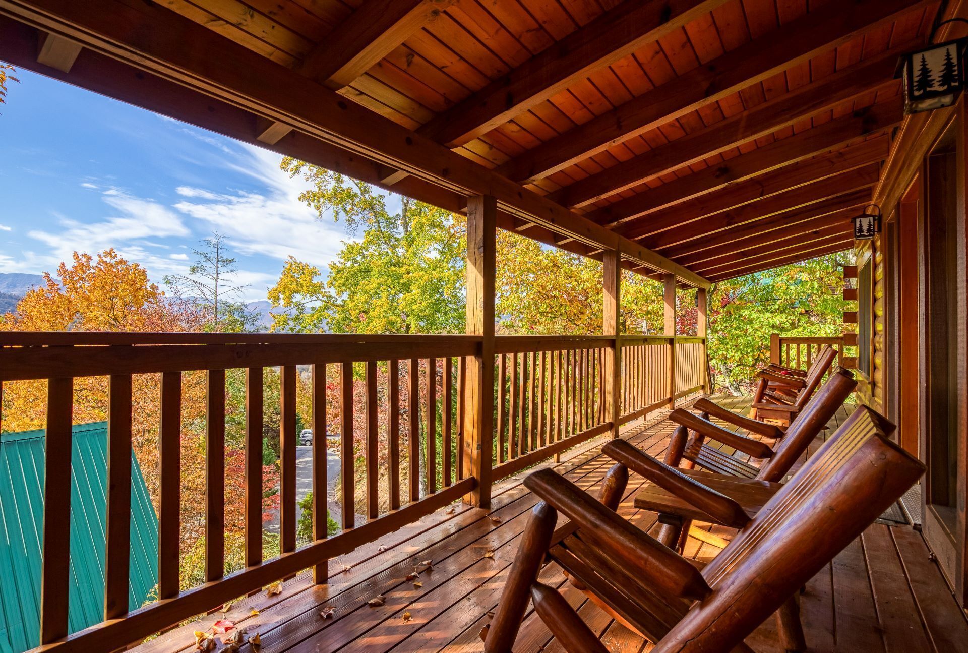 A wooden deck with benches and a view of autumn foliage.