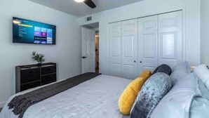 A bedroom with a bed, a TV mounted on the wall, a ceiling fan, and a wardrobe. - Peaceful Desert Villa - Lake View, Pool & Spa (Lake Havasu City)