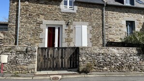 A stone house with a wooden gate, a small window, and a chimney.
