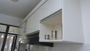 A modern kitchen with white cabinetry, a stainless steel range hood, and a built-in shelf with a container.