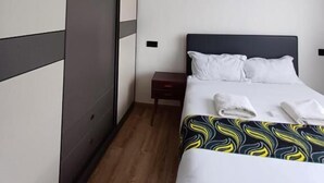 A hotel room with a bed, a nightstand, a wardrobe, and a door.