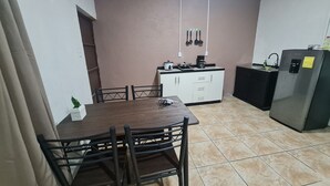 A compact kitchen with a dining table, chairs, a refrigerator, and a small countertop with a coffee maker. - Cabina en La Fortuna de San Carlos, Cabinas Guayabón #5, La Fortuna (La Fortuna)