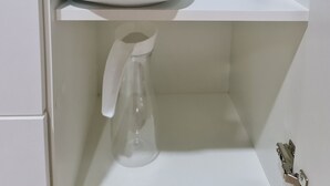 A white shelf with stacked plates and a clear glass bottle. - Cabina en La Fortuna de San Carlos, Cabinas Guayabón #5, La Fortuna (La Fortuna)
