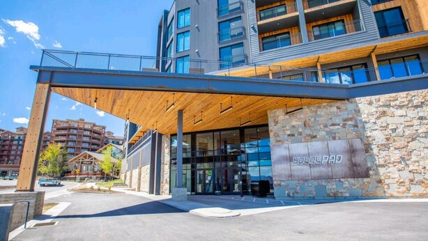 A modern building with a wooden overhang, stone facade, and multiple balconies. - Ski-in/Ski-out Canyon Haus Modern 1 bedroom- Pool, Hot Tub, Gym (Park City)
