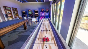 A shuffleboard table with three pucks, a pool table, and arcade games in a room with large windows. - Ski-in/Ski-out Canyon Haus Modern 1 bedroom- Pool, Hot Tub, Gym (Park City)