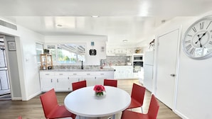 Una cucina moderna con mobili bianchi, un piano di lavoro in granito e un orologio grande appeso al muro.