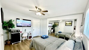 Una camera da letto moderna con un letto, una scrivania, una televisione e una ventola a soffitto.
