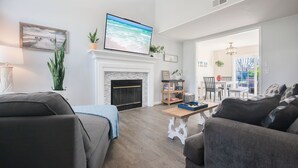 Un salon avec une cheminée, un téléviseur et un coin repas comprenant une table et des chaises.