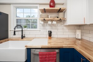 Une cuisine moderne avec un plan de travail en bois, un robinet noir et une serviette rouge accrochée à la porte.