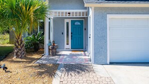 Une maison avec une porte d’entrée bleue, un garage et une véranda couverte.