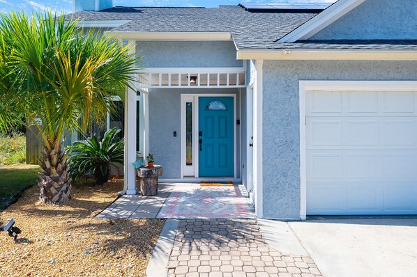 Une maison avec une porte d’entrée bleue, un garage et une véranda couverte.