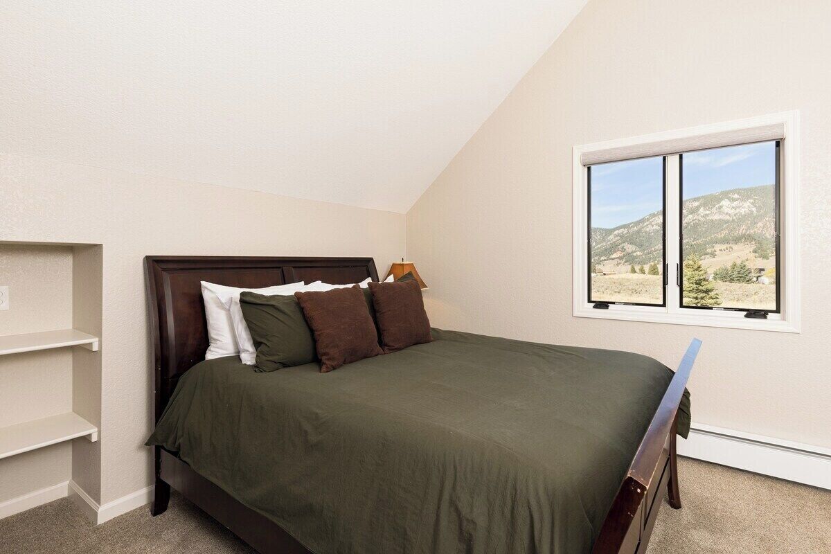 A bedroom with a bed, a window with a mountain view, and built-in shelves.