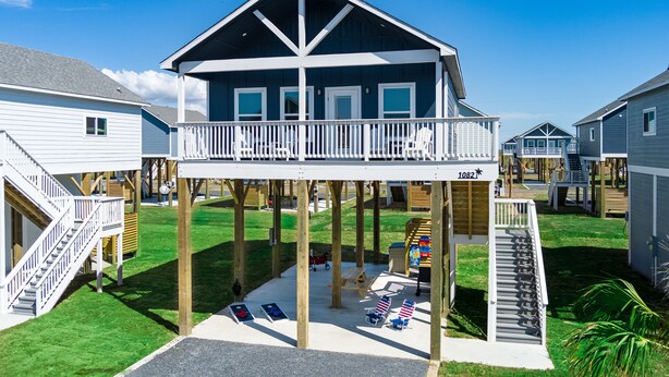 A two-story building with a balcony, wooden deck, and a small play area with a slide and a table.