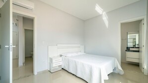 Ein Schlafzimmer mit Bett, Nachttisch, Kommode und einem Badezimmer mit Waschbecken und Spiegel.