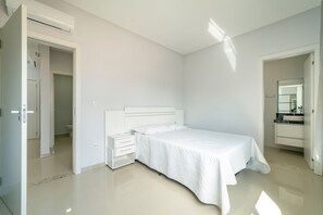 Une chambre à coucher comprenant un lit, une table de chevet, une commode et une salle de bain avec un lavabo et un miroir.