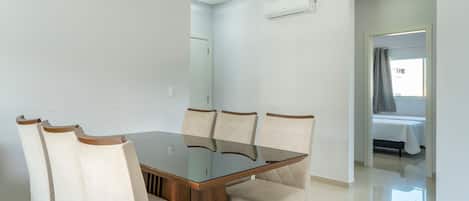 Un comedor moderno con una mesa de vidrio y seis sillas tapizadas.