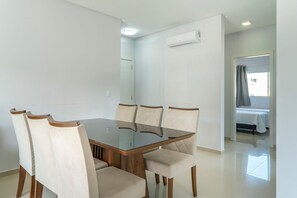 Un espace repas moderne avec une table à plateau en verre et six chaises rembourrées.