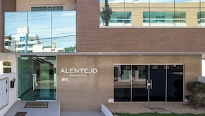 Een modern gebouw met een glazen ingang, waarop “ALENTEJO 357 RESIDENCIAL” staat.