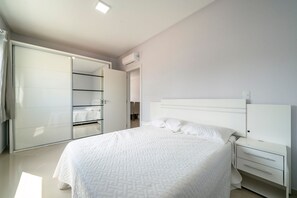 A bedroom with a large bed, a wardrobe, and a nightstand. - 1003A - Residencial Alentejo - Apto 201 (Bombinhas)