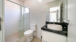 Ein modernes Badezimmer mit Duschkabine aus Glas, einer weißen Toilette und einem Waschtisch mit großem Spiegel.