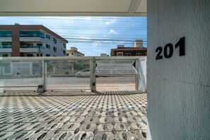 Un bâtiment sur lequel on peut voir le numéro « 201 » sur un mur, une entrée fermée par un portail et une zone pavée avec un motif décoratif.