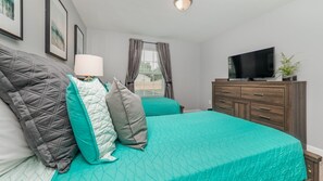 A bedroom with two beds, a TV, a dresser, and a window with curtains. - 1562 Moon Valley Drive (Davenport)