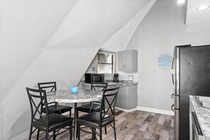 A kitchen with a dining table and chairs, a refrigerator, and a microwave. - Short Walk To Beach | Additional Studio (Panama City Beach)