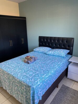 A bedroom with a bed, a wardrobe, and a bedside table. - Residencial Karine Apto 102  (Joinville)