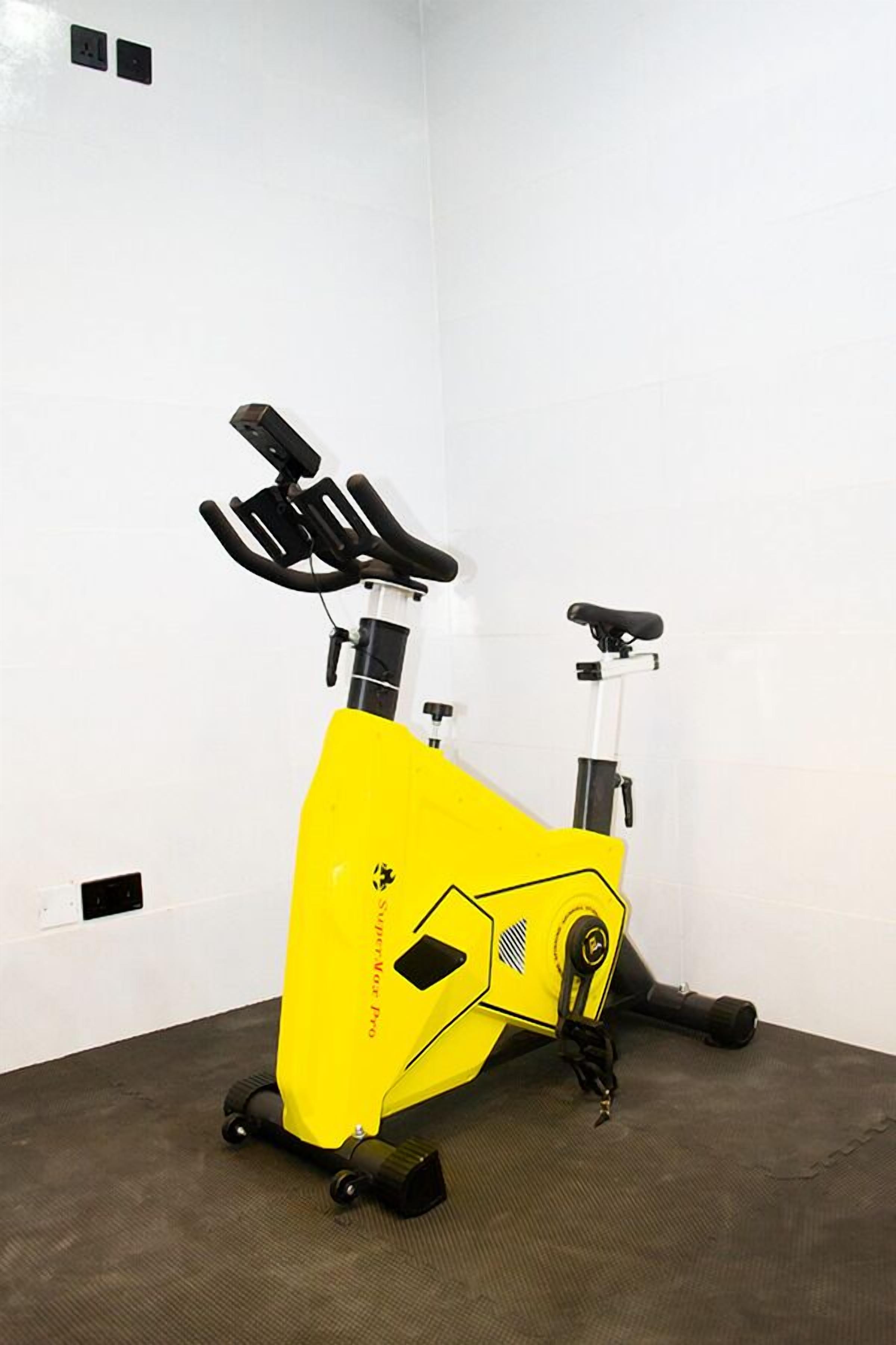 A stationary exercise bike in a room with white walls and a grey floor.