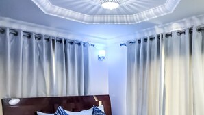 A hotel room with a large bed, a wooden headboard, and a chandelier. - Hotel Medallion (Lekki)