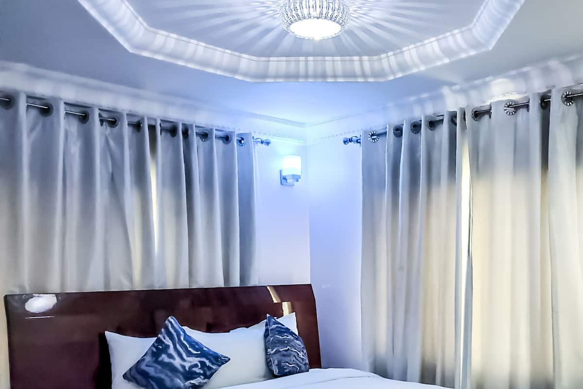 A hotel room with a large bed, a wooden headboard, and a chandelier.