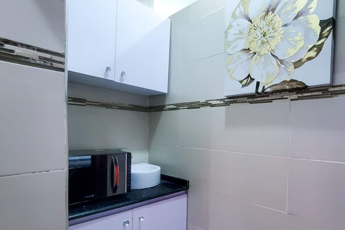 A kitchen with white cabinets, a microwave, and a sink.