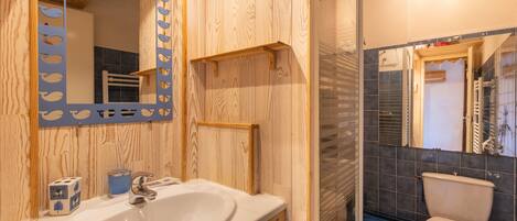 A bathroom with a wooden vanity, a sink, a mirror, and a toilet.