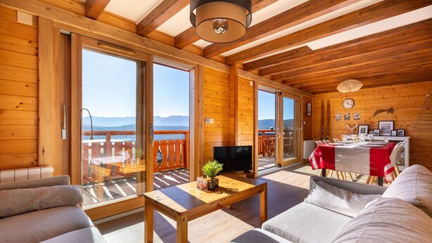 A wooden cabin with a sofa, a table, and a TV in the living area.