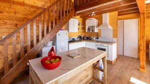 A wooden interior with a kitchen area, a marble countertop, and a red bowl of fruit.
