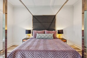 Une chambre à coucher moderne avec un grand lit, deux tables de chevet et une tête de lit.