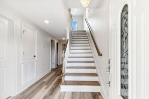 Una escalera con paredes blancas y escalones de madera que lleva a una plataforma.