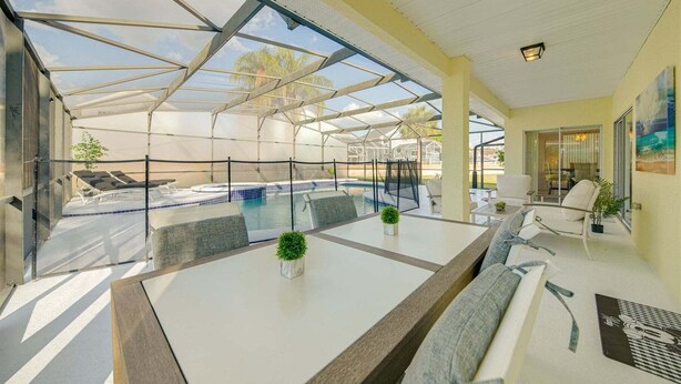 Un área de piscina techada con sillones de descanso y una mesa.