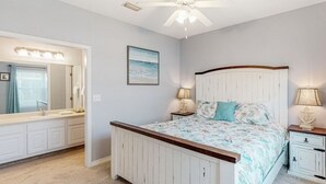 A bedroom with a bed, a nightstand, a dresser, a mirror, and a ceiling fan.