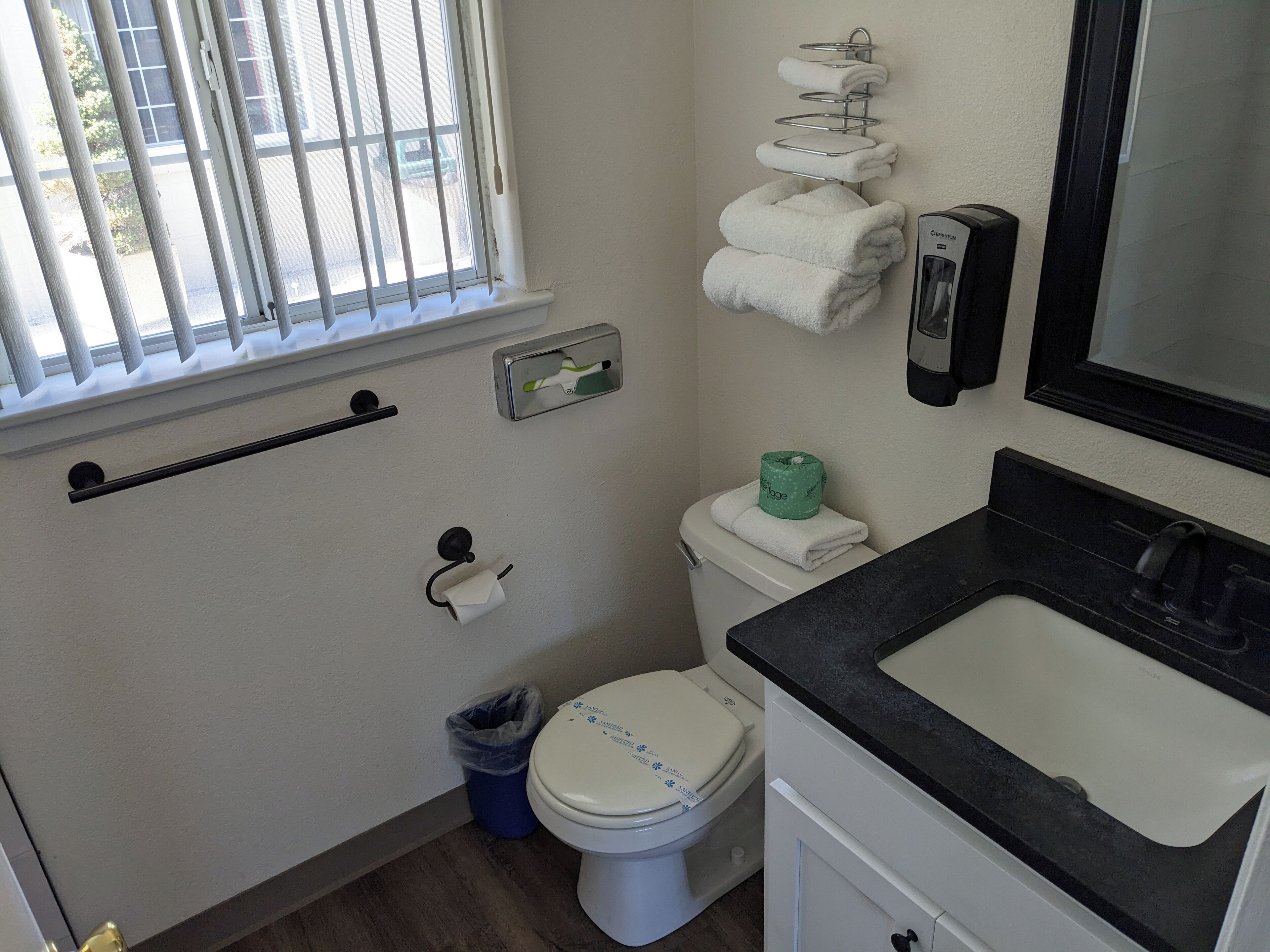A bathroom with a toilet, sink, and window with bars.