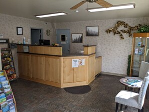 A reception area with a wooden counter, a computer, a clock, and a sign offering breakfast, burrito, or dinner burrito.