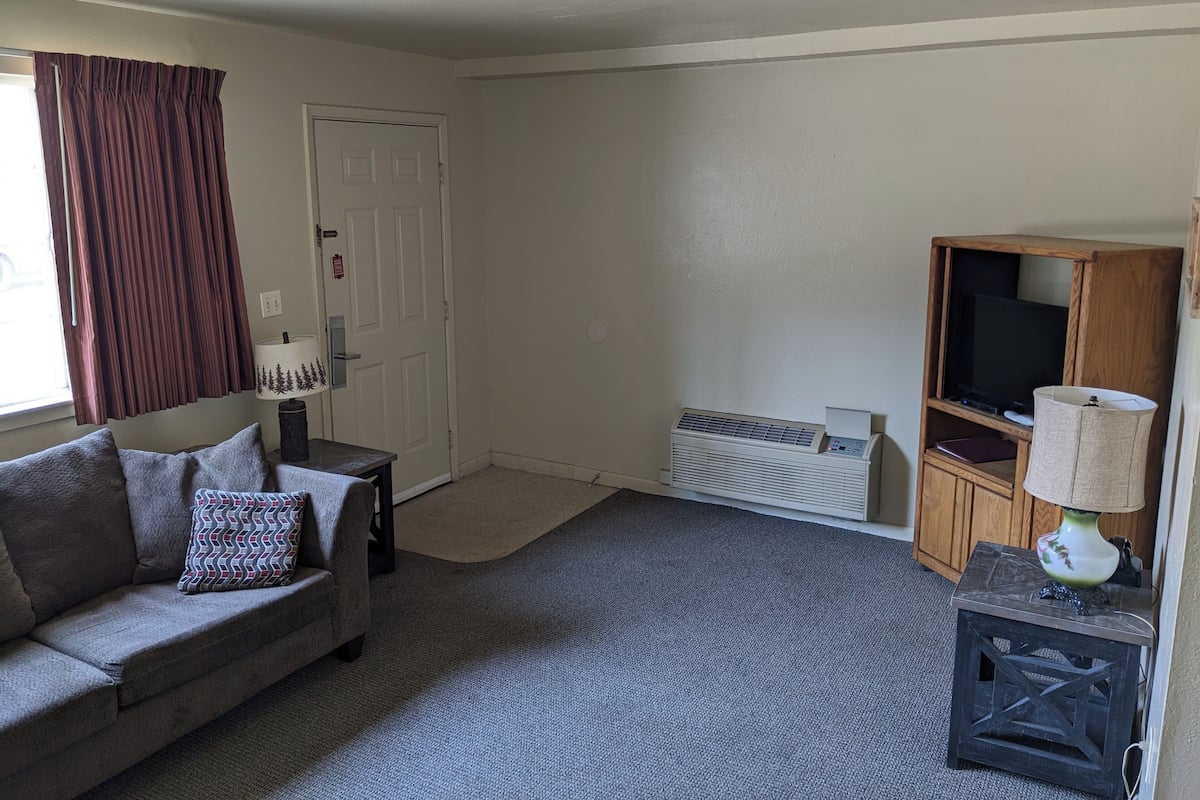 A living room with a sofa, a small table, a TV stand, and a radiator.