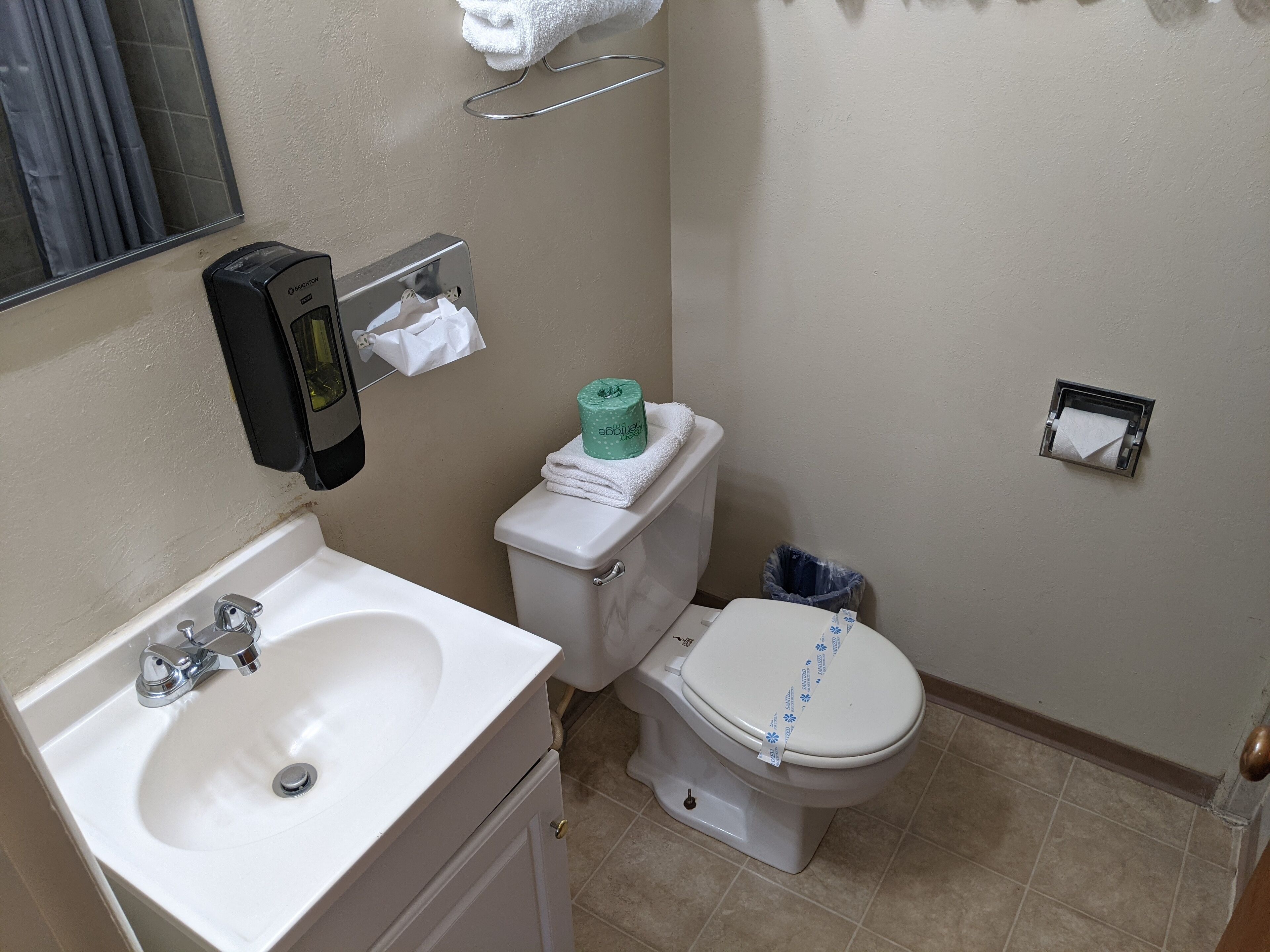 Casa de banho com lavatório branco, sanita e um porta-toalhas.