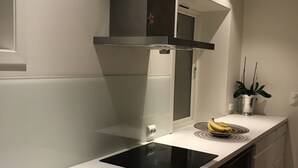 Una cucina moderna con piano cottura a induzione nero, elettrodomestici in acciaio inossidabile e un piano di lavoro bianco.