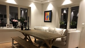 Un'accogliente zona giorno con un tavolo e una panca in legno, un divano bianco e un quadro appeso al muro.