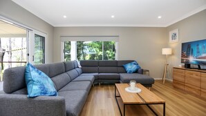 Una sala de estar moderna con un sofá seccional gris, una mesa de centro de madera y un televisor sobre un mueble de madera.
