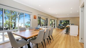 Una cocina moderna con comedor, ventanas amplias y vista a árboles y un lago.