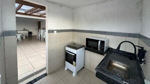 Cocina compacta con estufa a gas, microondas y pileta.
