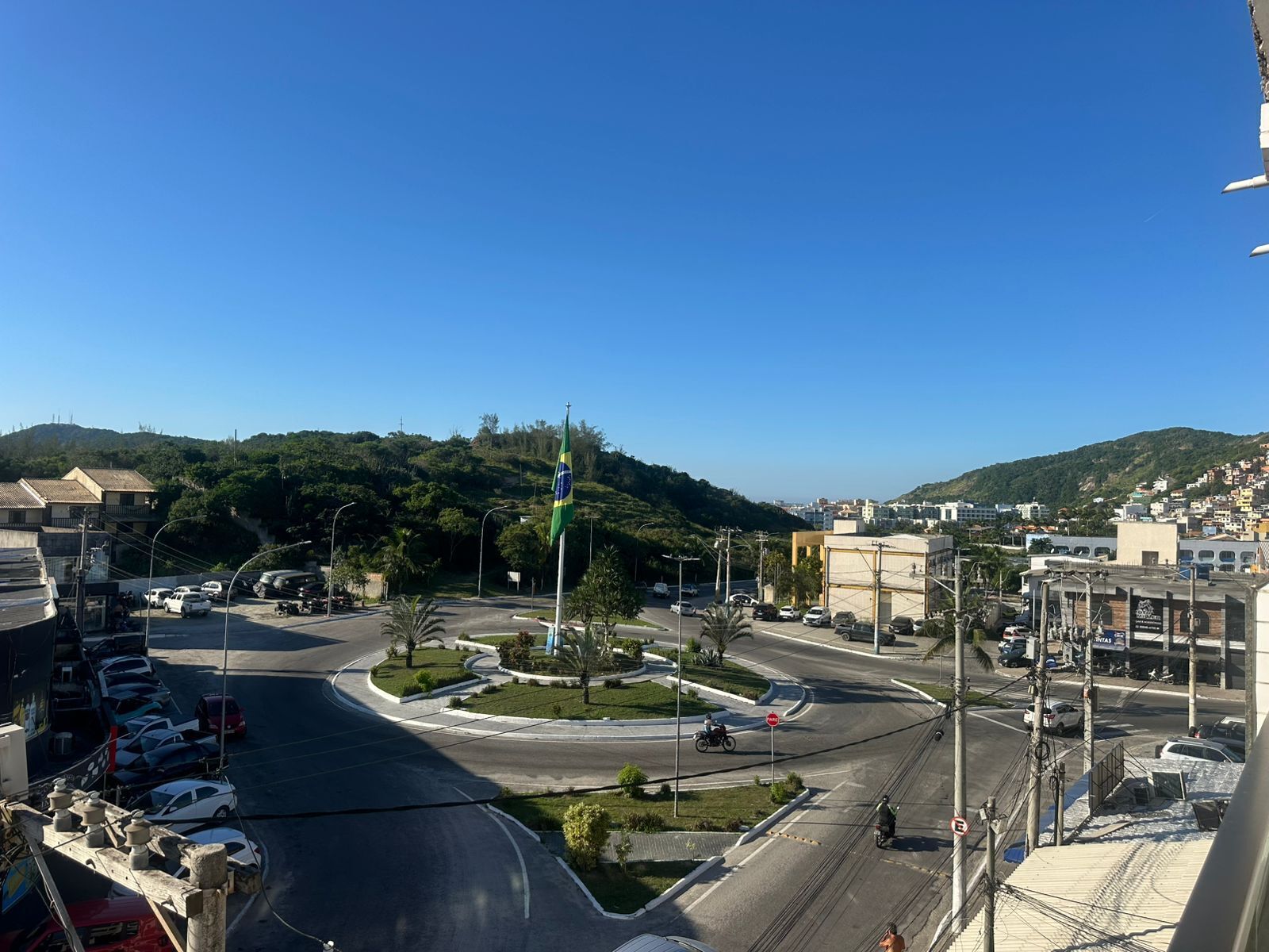 A cityscape with a roundabout, buildings, and a hill in the background.