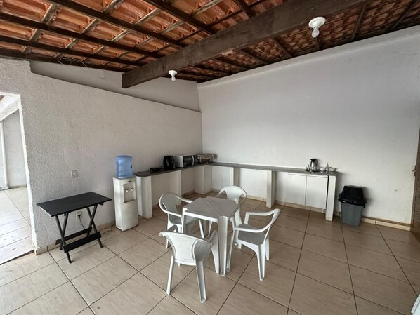 Una cocina y comedor integrados, de tamaño pequeño, con piso de baldosas, paredes blancas y techo de madera.